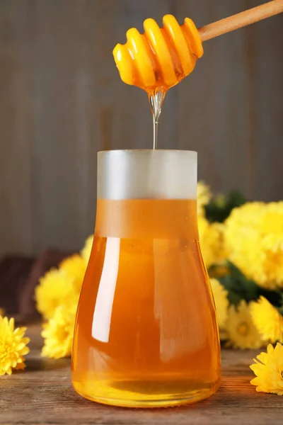 Potje met biologische honing en chrysanten bloemen op houten tafel — Stockfoto