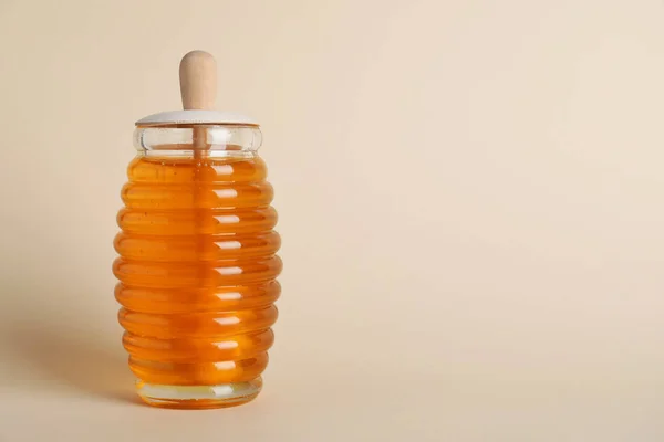 Sebotol madu organik dengan celup pada latar beige. Ruang untuk — Stok Foto