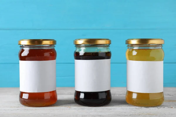 Jars of organic honey with blank labels on wooden table against — Stock Photo, Image