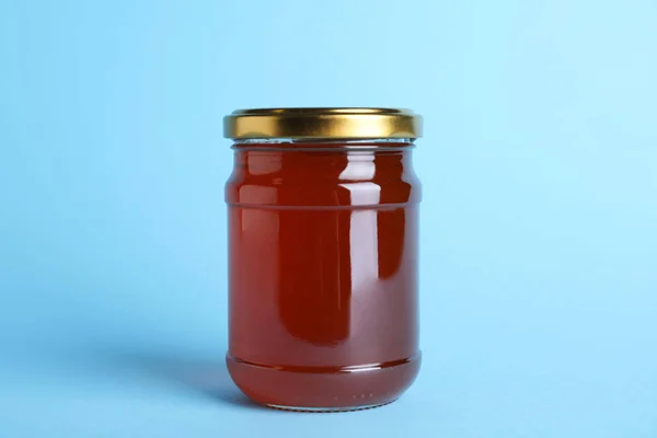 Jar of organic honey on light blue background — Stock Photo, Image