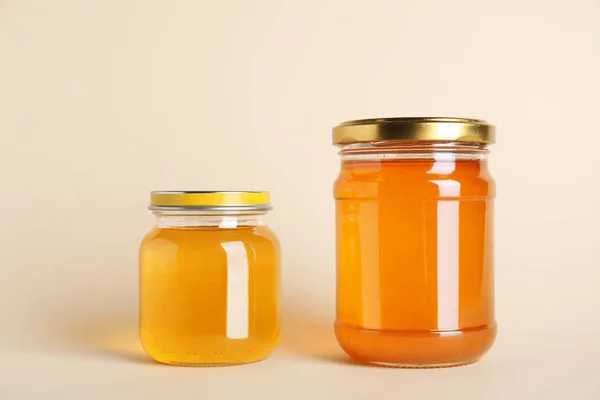 Frascos con diferentes tipos de miel orgánica sobre fondo beige — Foto de Stock