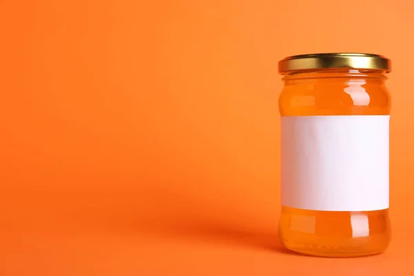 Frasco de mel orgânico com rótulo em branco sobre fundo laranja. Espada. — Fotografia de Stock