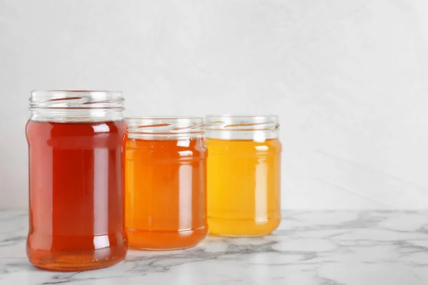 Баночки з різними видами органічного меду на мармуровому столі знову — стокове фото