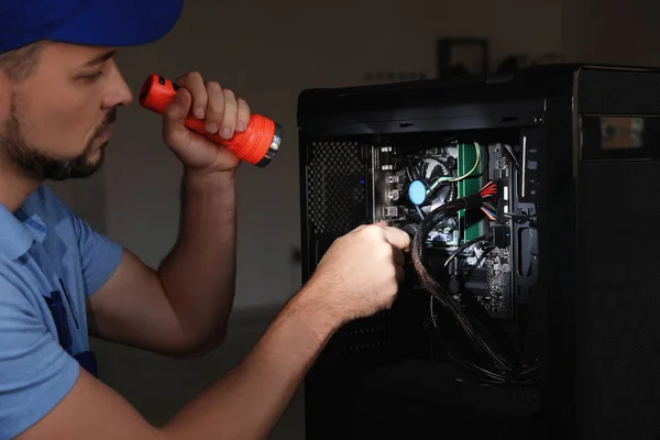 Repairman with flashlight fixing system unit indoors, closeup