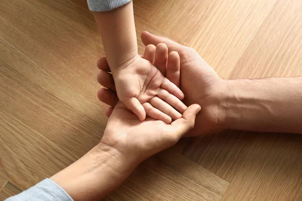 Ευτυχισμένη Οικογένεια Κρατώντας Χέρια Ξύλινο Φόντο Closeup — Φωτογραφία Αρχείου