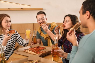 Bir grup arkadaş kafede lezzetli pizzalarla eğleniyorlar.