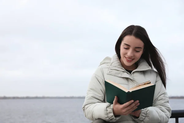 Bulutlu Bir Günde Nehir Kenarında Kitap Okuyan Bir Kadın — Stok fotoğraf