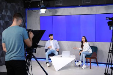 Sunucular ve kamera operatörü stüdyoda çalışıyor. Haber yayını