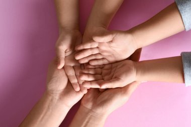 Mutlu aile pembe arka planda el ele tutuşuyor.