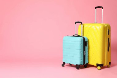 Pembe arka planda şık sarı ve turkuaz bavullar. Boşluk