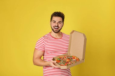 Sarı arka planda lezzetli pizzalı yakışıklı bir adam.