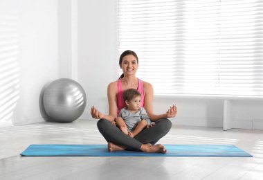 Genç bir kadın oğluyla meditasyon yapıyor.