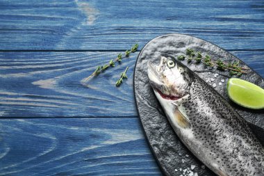 Mavi ahşap masada çiğ, cani alabalık balığı, düz yerde. Metin için boşluk