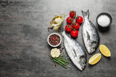 Gri masa üzerinde çiğ dorada balığı ile düz bileşim, metin için boşluk