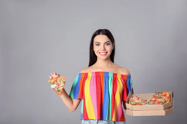 Beautiful woman with pizza on grey background