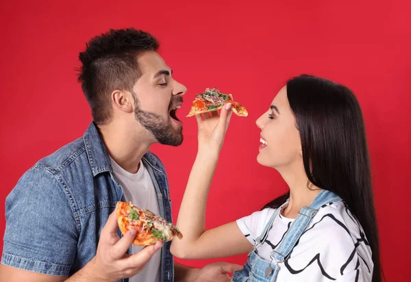 Happy young couple with pizza on red background