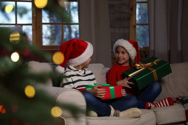 Glückliche Kinder Mit Weihnachtsmützen Und Weihnachtsgeschenken Auf Dem Heimischen Sofa — Stockfoto