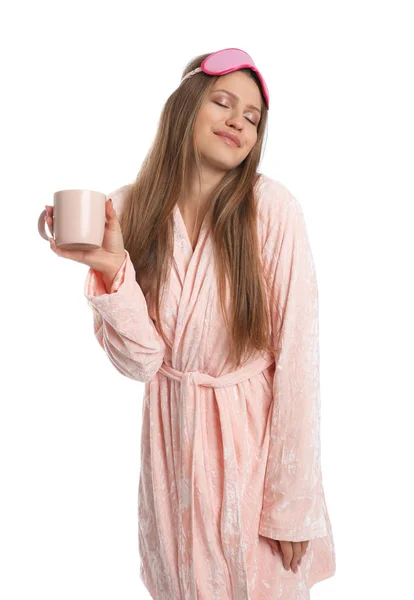 Jovem mulher em roupão de banho com máscara de sono e xícara de bebida em w — Fotografia de Stock