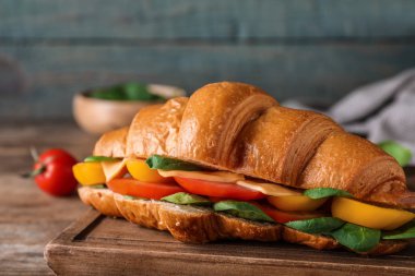 Ahşap masada lezzetli kruvasan sandviçi, yakın plan.