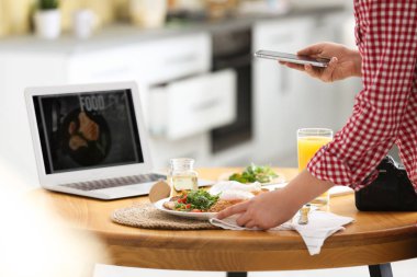 Yemek blogcusu öğle yemeğini içeride, ahşap masada çekiyor.