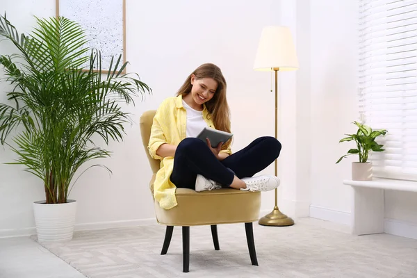 Jonge vrouw met tablet rustend in fauteuil thuis — Stockfoto