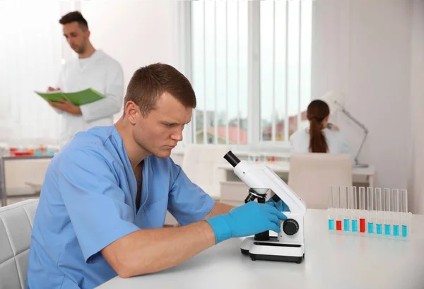 Mikroskop kullanan bilim adamı ve laboratuardaki meslektaşları.. — Stok fotoğraf