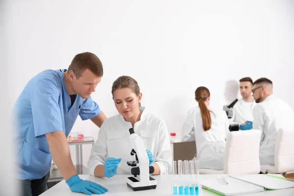 Medical students working with microscope in modern laboratory — Stock Photo, Image