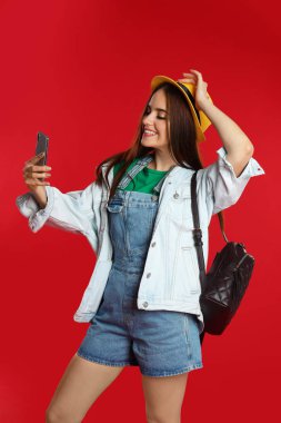 Kırmızı arka planda selfie çeken genç bir kadın.