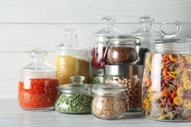 Cam kavanozlar ve beyaz ahşap masadaki makarna çeşitleri.