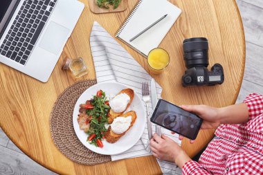Yemek blogcusu öğle yemeğini ahşap masada çekiyor.