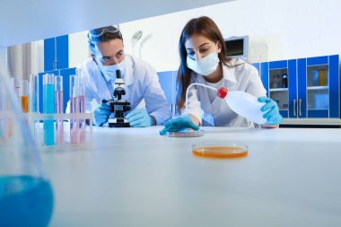 Laboratuvarda mikroskopla araştırma ve analiz yapan bilim adamları