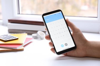 Akıllı telefondaki takvim uygulamasını kullanan kadın kapalı alanda, yakın plan