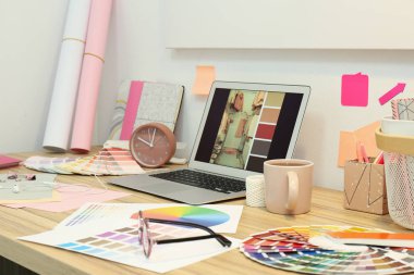 Modern dizüstü bilgisayarı ve renk paletleri olan tasarımcı işyeri 