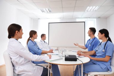 Doktorlar konferans sırasında kapalı alanda video projektörü kullanıyorlar.
