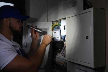 İçerideki elektrik panelini tamir eden fenerli bir elektrikçi.