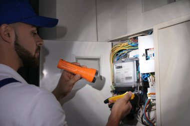 İçerideki elektrik panelini tamir eden fenerli bir elektrikçi.