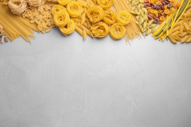 Açık gri masada farklı türde makarna, düz. Boşluk