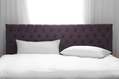 Pencerenin yanında yumuşak yastıklı modern yatak