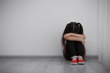 Üzgün küçük kız içeride yerde oturuyor, mesaj için yer var. Çocuk tehlikede.