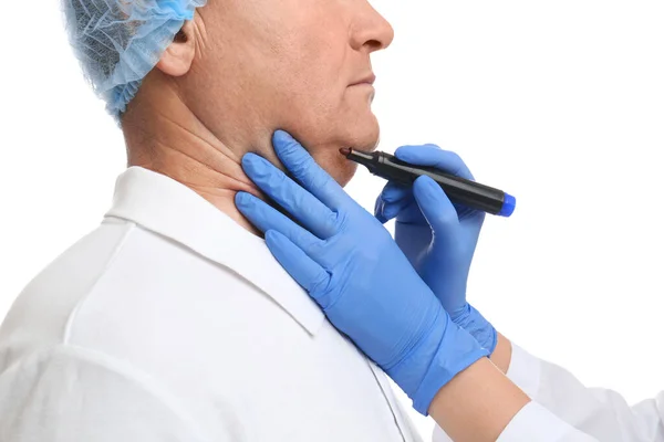 Surgeon with marker preparing man for operation against white ba — Stock Photo, Image