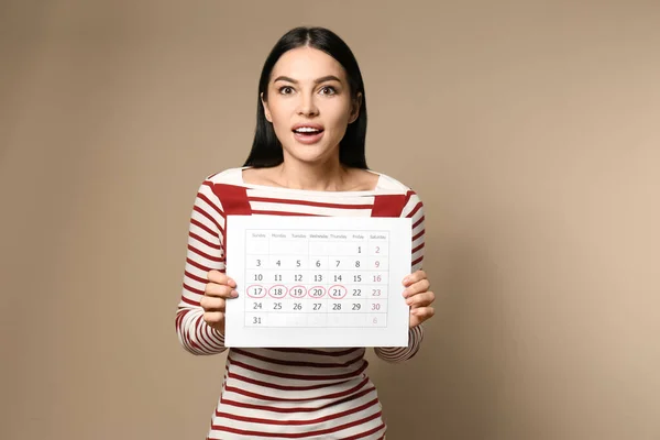 Ung Kvinna Innehav Kalender Med Markerade Menstruationscykel Dagar Beige Bakgrund — Stockfoto