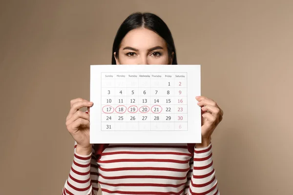 Молодая Женщина Проводит Календарь Отмеченными Днями Менструального Цикла Бежевом Фоне — стоковое фото