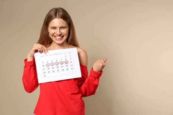 Возбужденная Молодая Женщина Проводит Календарь Отмеченными Днями Менструального Цикла Бежевом — стоковое фото