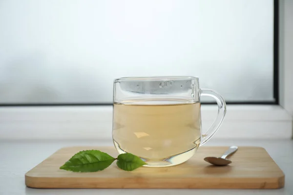 Tasty hot green tea in cup on window sill, closeup — Stock Photo, Image