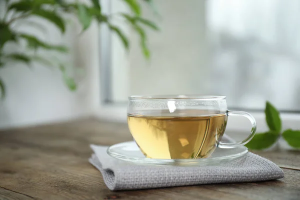Leckerer heißer grüner Tee in Tasse auf Holztisch — Stockfoto