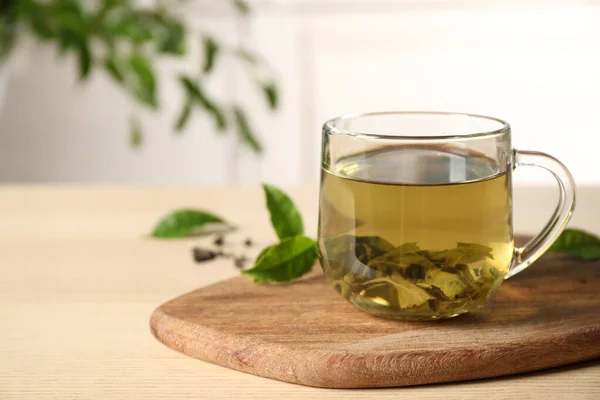 Leckerer heißer grüner Tee in Tasse auf Holztisch, Nahaufnahme — Stockfoto