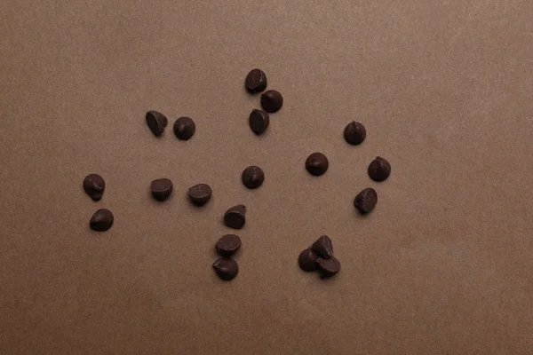Смачні шоколадні чіпси на коричневому фоні, вид зверху — стокове фото
