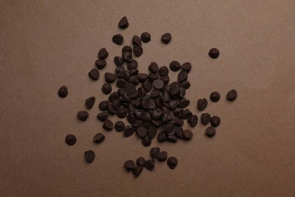 Pile των νόστιμων τσιπ σοκολάτας σε καφέ φόντο, top view — Φωτογραφία Αρχείου