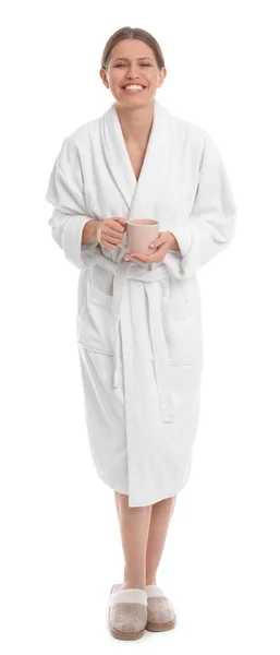 Young woman in bathrobe with cup of beverage on white background — Stock Photo, Image