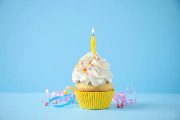 Läcker födelsedag cupcake med ljus på ljusblå bakgrund — Stockfoto